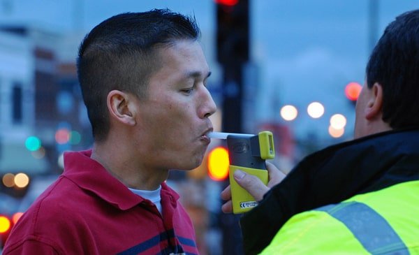 Police giving a DUI suspect a breath test on the side of the road.