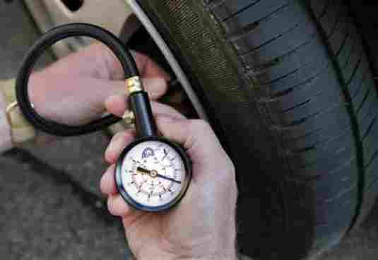 showing a person checking their vehicle's tire pressure